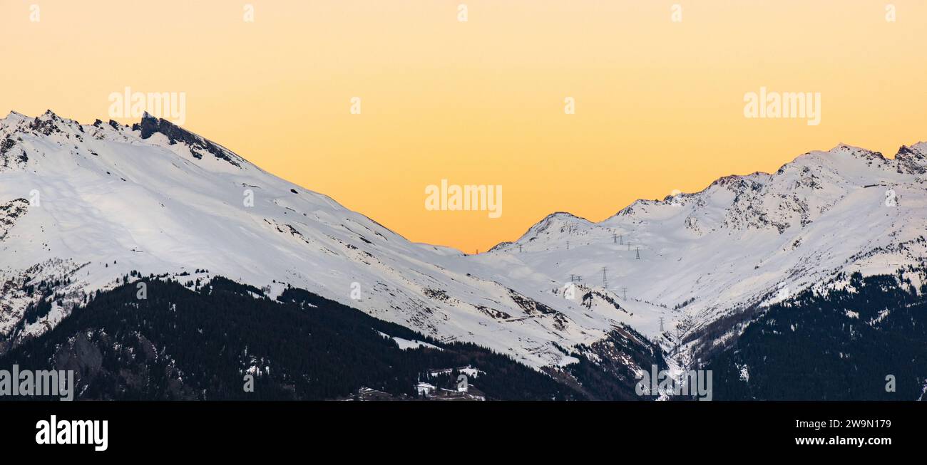 Sonnenuntergang auf dem verschneiten Berggipfel im Alpental Stockfoto