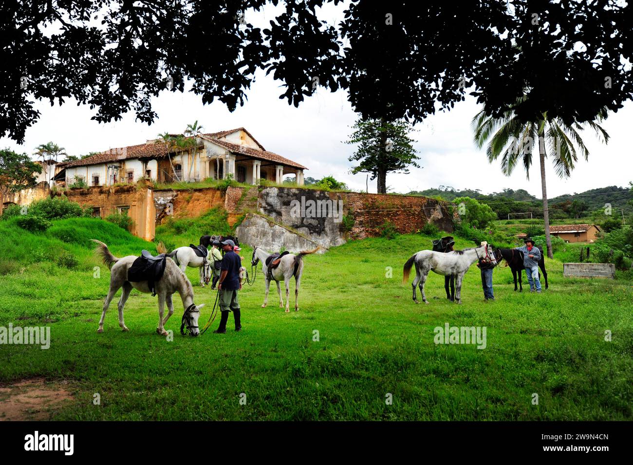 Eine Gruppe von Menschen mit ihren Pferden steht neben alten Hacienda-Ruinen in der Landschaft von Chiapas, Mexiko. Stockfoto