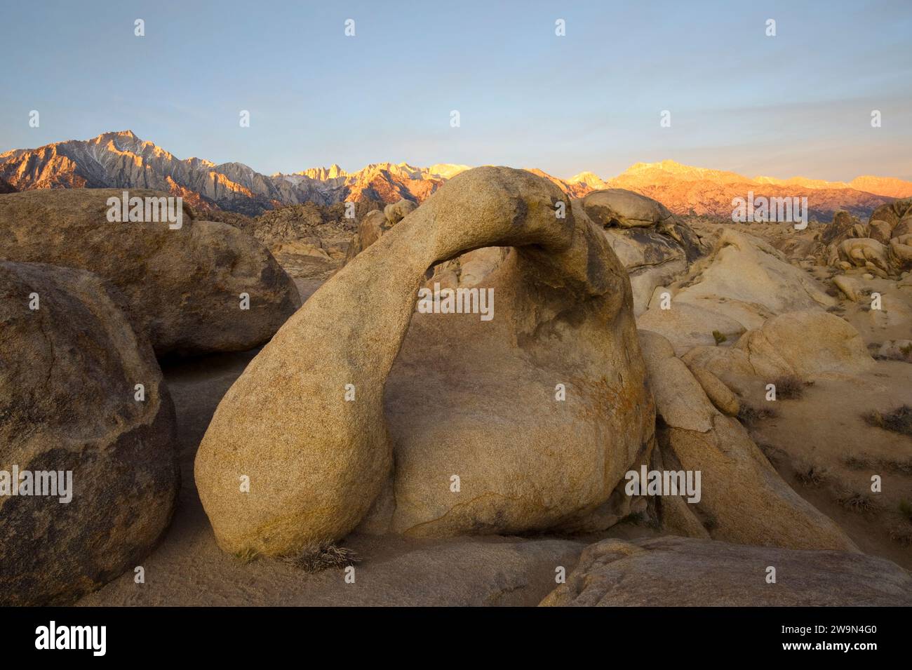 Die östliche Sierra Nevada wird bei Sonnenaufgang mit dem Mobius Arch im Vordergrund in den Alabama Hills, CA. Stockfoto