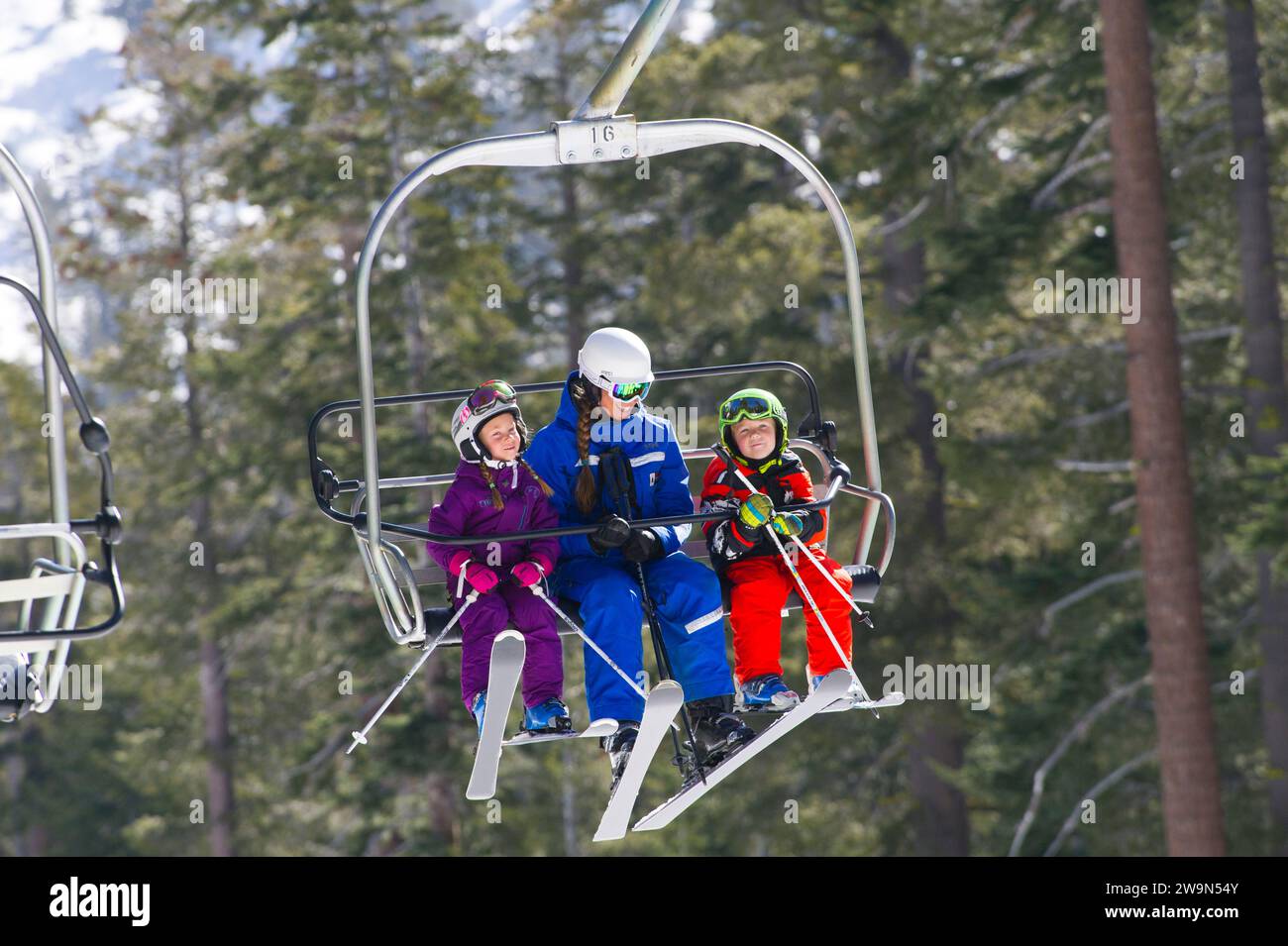 Zwei junge Skifahrer fahren mit ihrem Skilehrer in den Sessellift, während sie eine Lektion im Kirkwood Mountain Resort in Kirkwood, Kalifornien, nehmen. Stockfoto