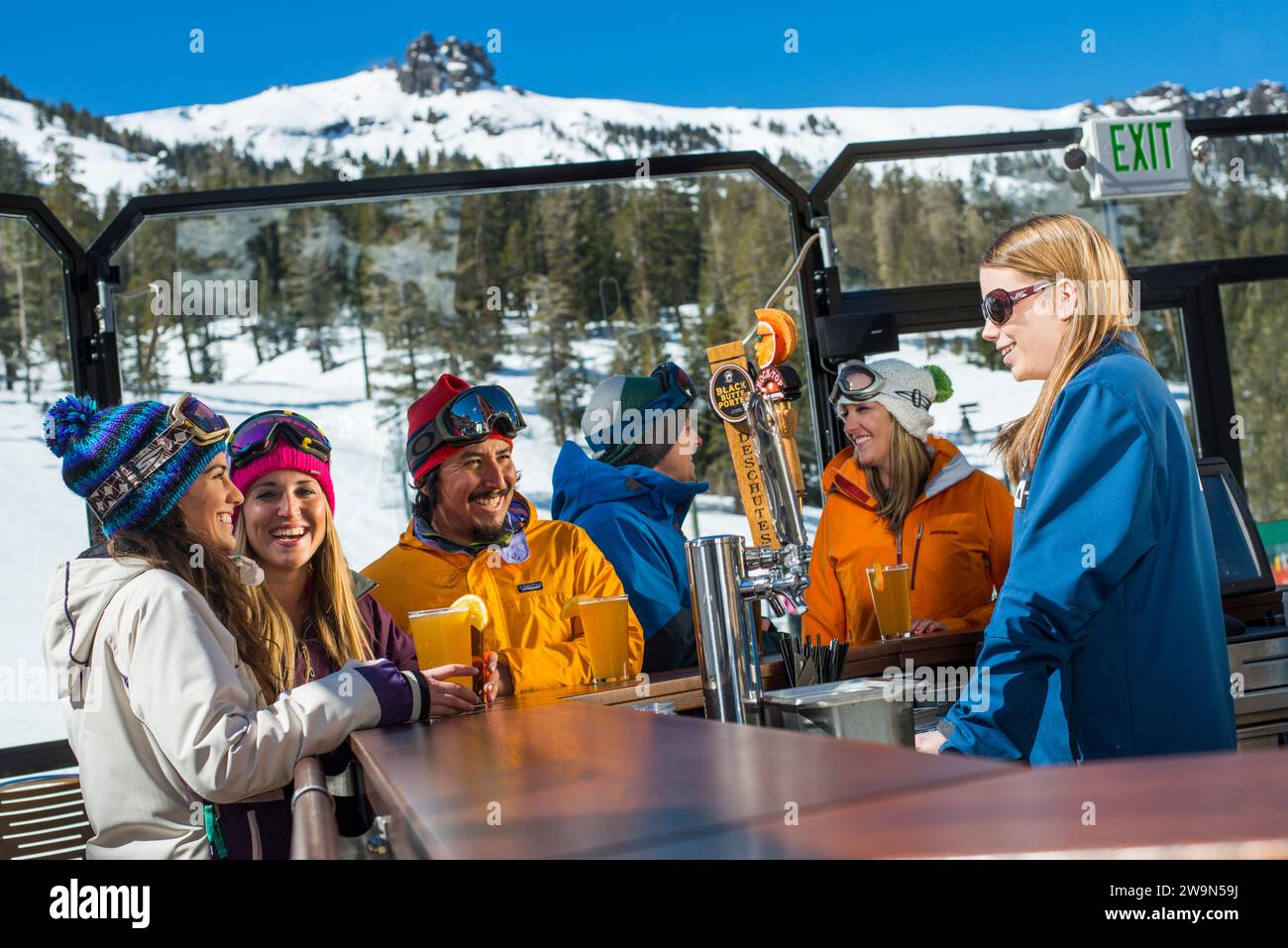 Eine Gruppe von Freunden genießt eine Runde Bier in der Umbrella Bar im Kirkwood Mountain Resort während eines Apres Ski im Winter in Kirkwood, Kalifornien. Stockfoto