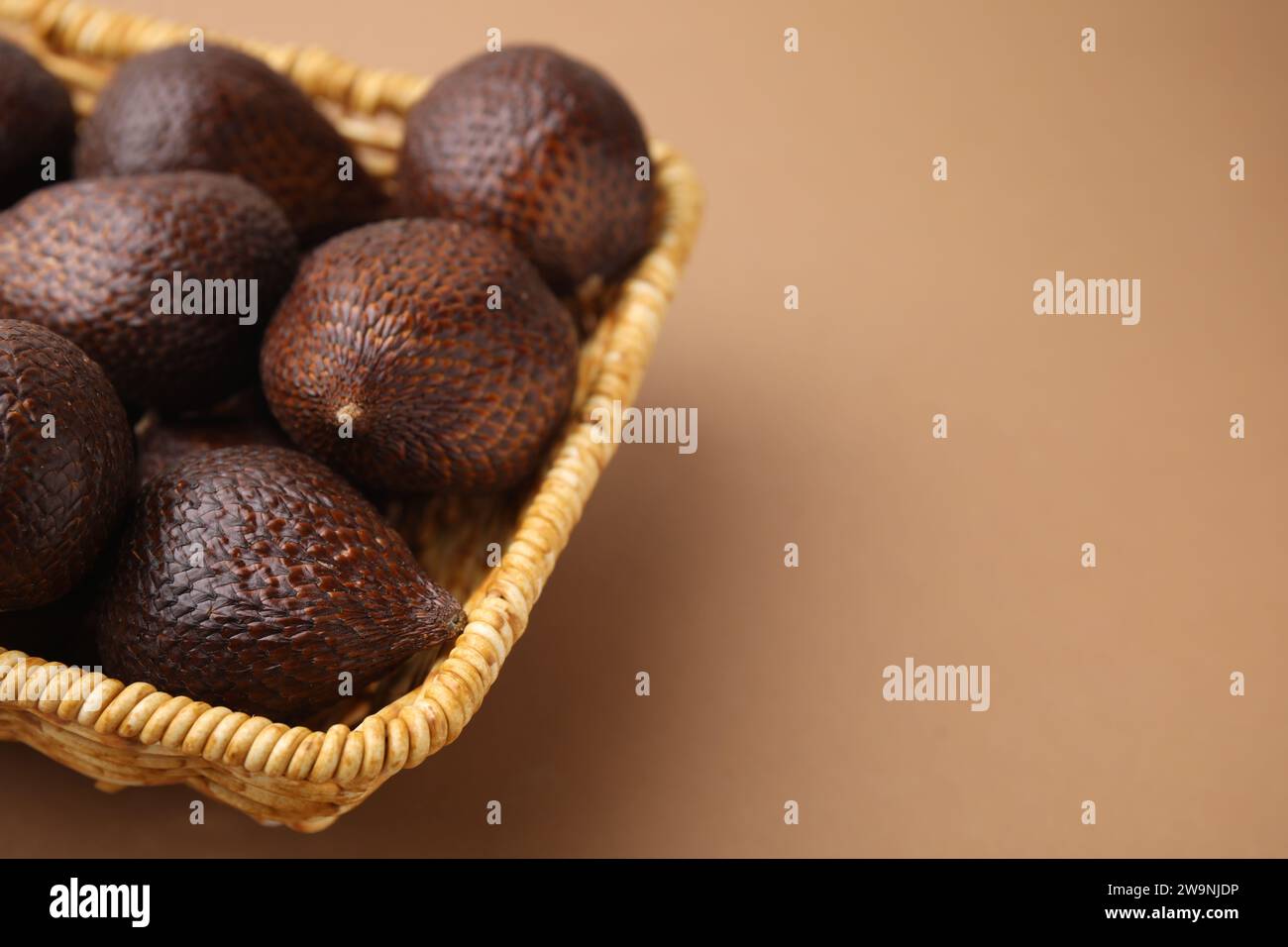 Köstliche salakfrüchte im Korb auf hellbraunem Hintergrund, Nahaufnahme. Leerzeichen für Text Stockfoto