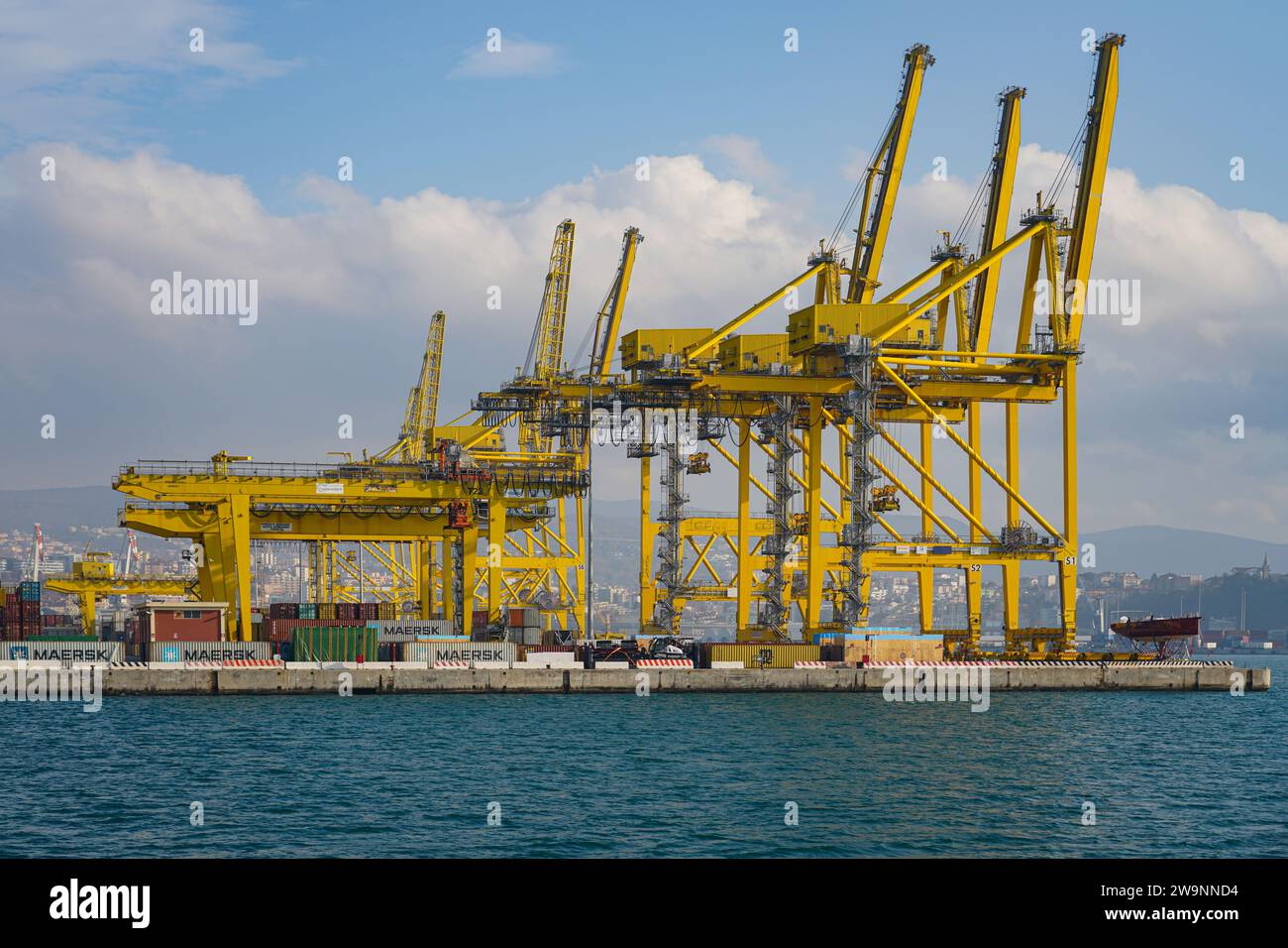 Gelbe Kräne in der Nähe von Containern an einem Kai im Hafen von Triest. Stockfoto