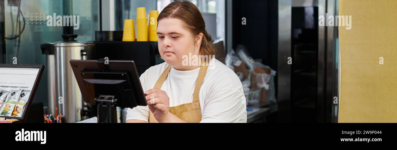 Junge Angestellte mit geistiger Behinderung, die Bargeldterminal während der Arbeit im Café betreibt, Banner Stockfoto