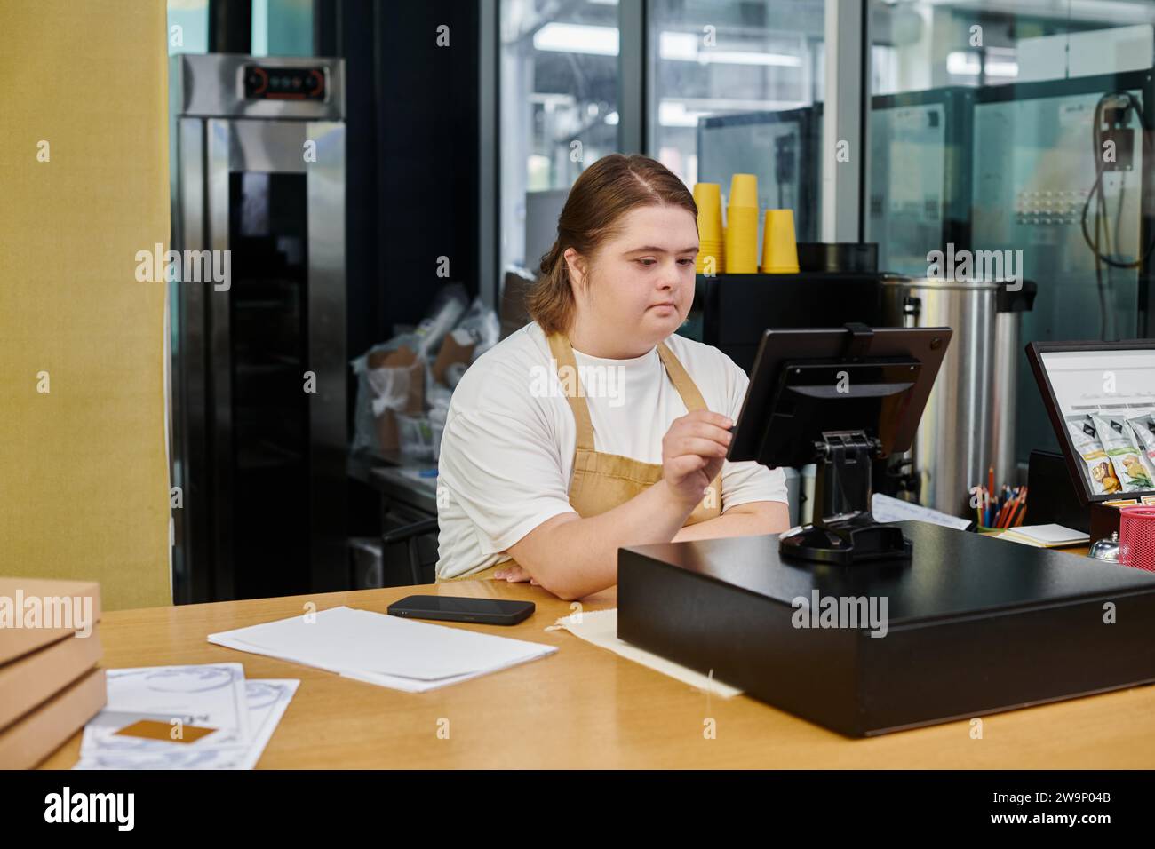 Aufmerksame Angestellte mit psychischen Störungen, die Bargeld-Terminal während der Arbeit in modernen Cafés betreibt Stockfoto