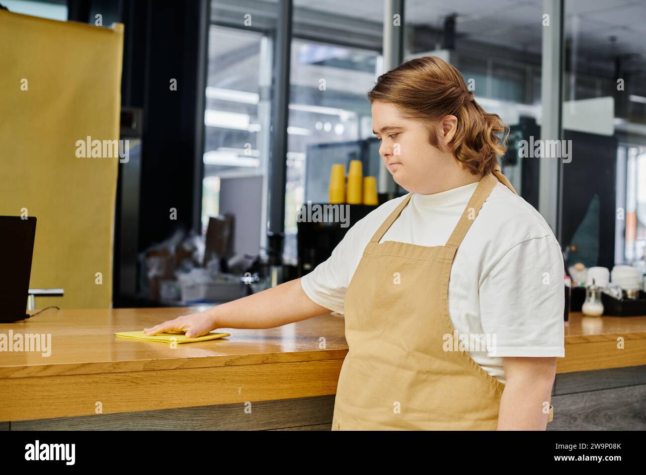 Junge Angestellte mit psychischen Störungen, die in modernen Cafés und Putztheken mit Lappen arbeitet Stockfoto