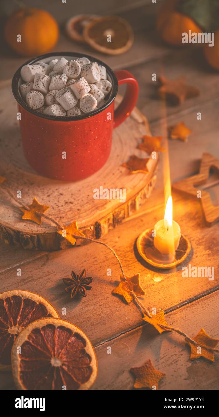 Niedliche, gemütliche Winterkomposition. Rote Tasse, Marshmallows, Weihnachtsbeleuchtung und Kerze. Silvester und weihnachten, Wärme, Komfort Stockfoto