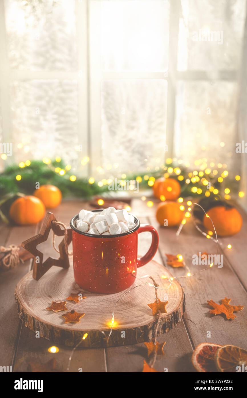 Niedliche, gemütliche Winterkomposition. Rote Tasse, Marshmallows, Orangen und Weihnachtslichter. Silvester und weihnachten, Wärme, Komfort Stockfoto