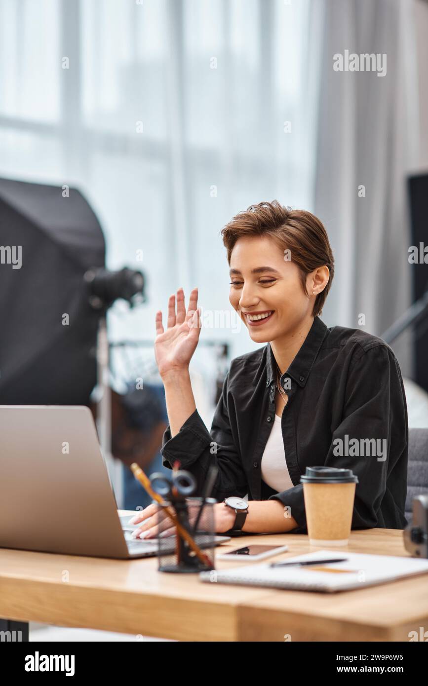Glückliche, attraktive Fotografin in lässiger Kleidung, die Videoaufnahmen hat und fröhlich lächelt Stockfoto