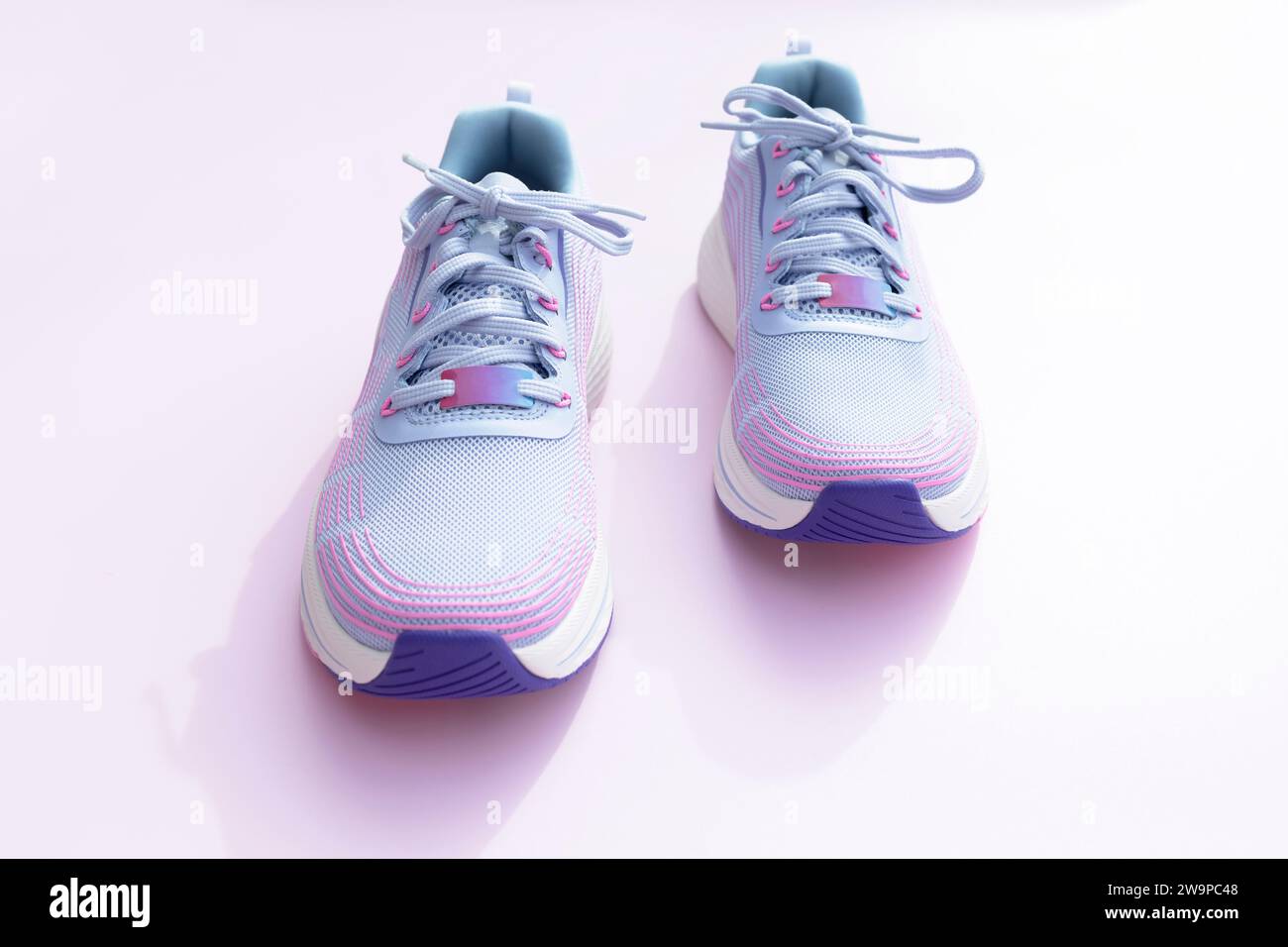 Violette blaue sportliche Laufschuhe für Frauen auf rosa Hintergrund. Mode, Trainingsschuhe für das Fitnessstudio, Schuhe für Damen. Nationalschuh Der Welttag Stockfoto