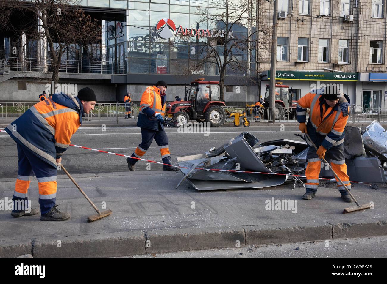 Kiew, Ukraine. Dezember 2023. Kommunale Arbeiter sammeln am Ort einer russischen Raketenexplosion in Kiew Trümmer von Gebäudefassaden und zerstörten Autos. Quelle: SOPA Images Limited/Alamy Live News Stockfoto