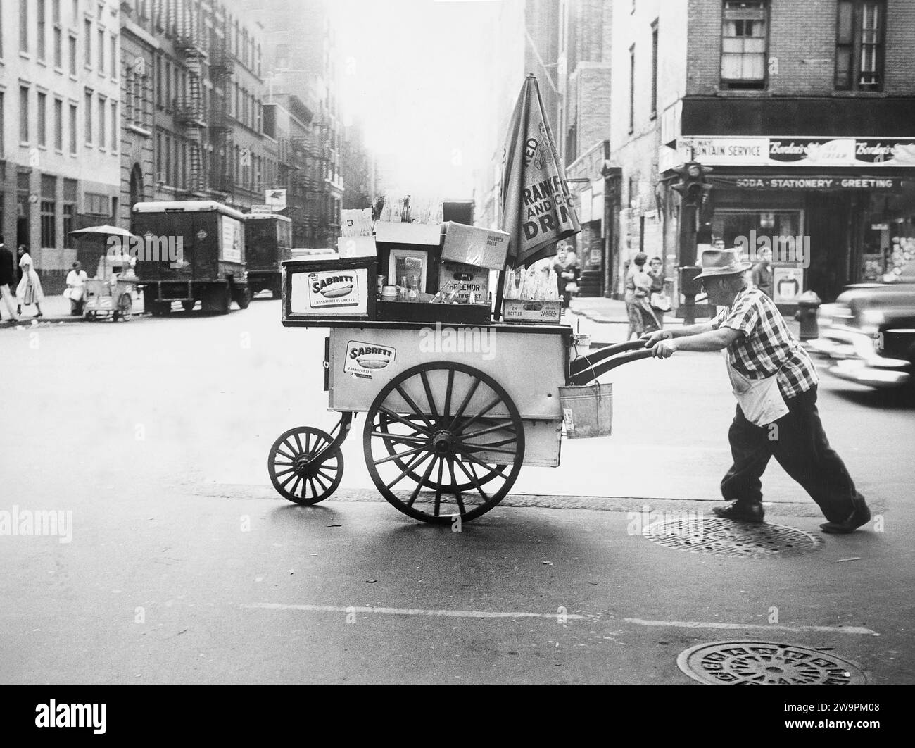 Mann schiebt Hotdog-Wagen auf die andere Straßenseite, New York City, New York, USA, Angelo Rizzuto, Anthony Angel Collection, September 1957 Stockfoto