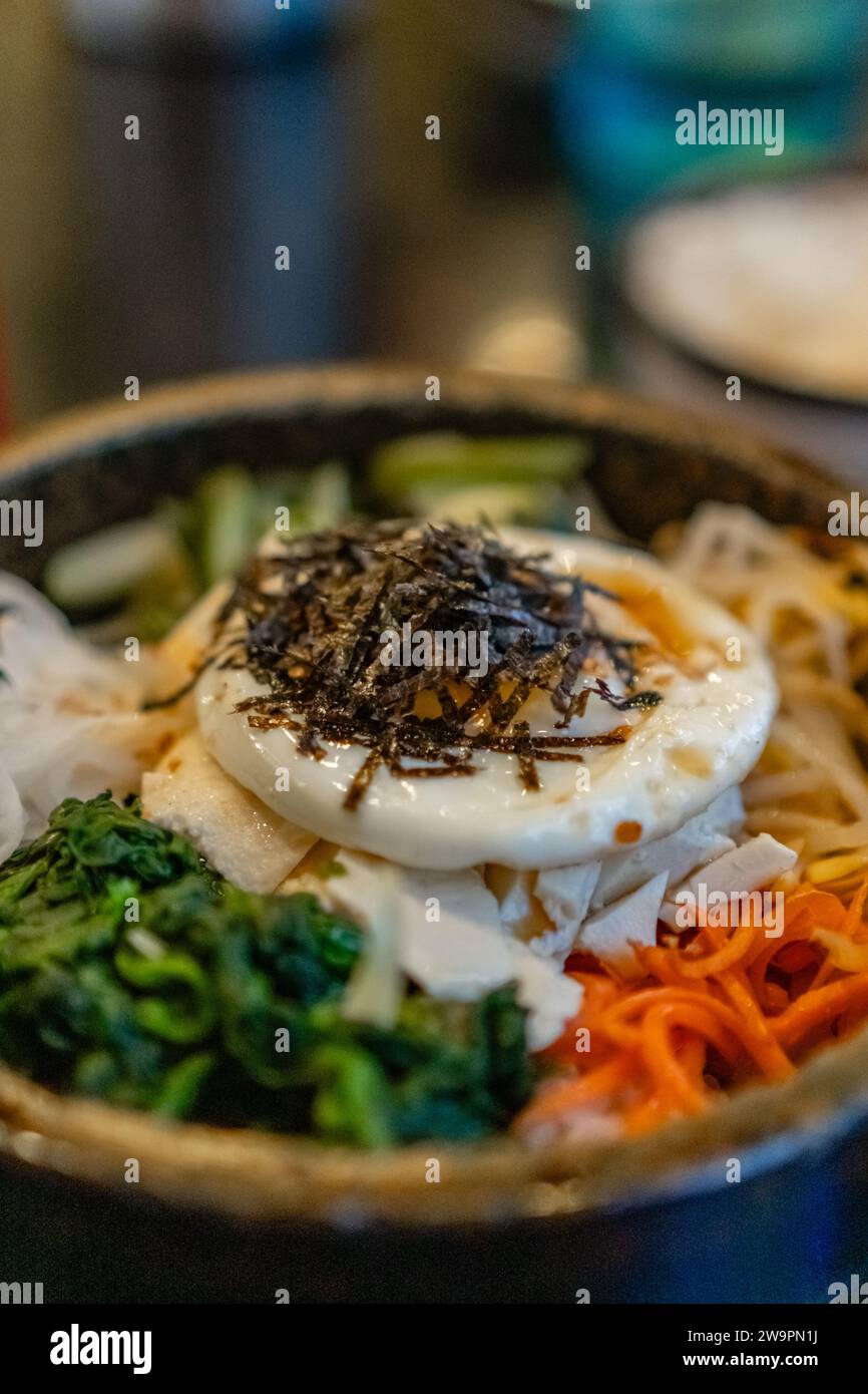 Koreanischer vegetarischer Bibimbap, gebratener Tofu und Gemüse in einer heißen Steinschale. Stockfoto