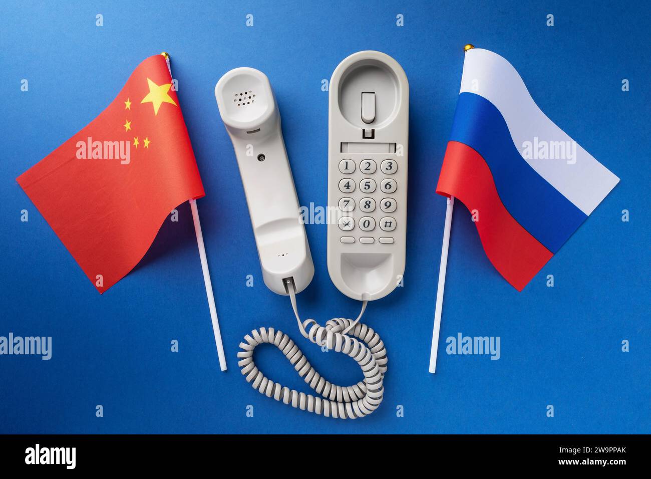 Telefon und zwei Flaggen auf blauem Hintergrund, Konzept zum Thema Telefongespräche zwischen China und Russland Stockfoto