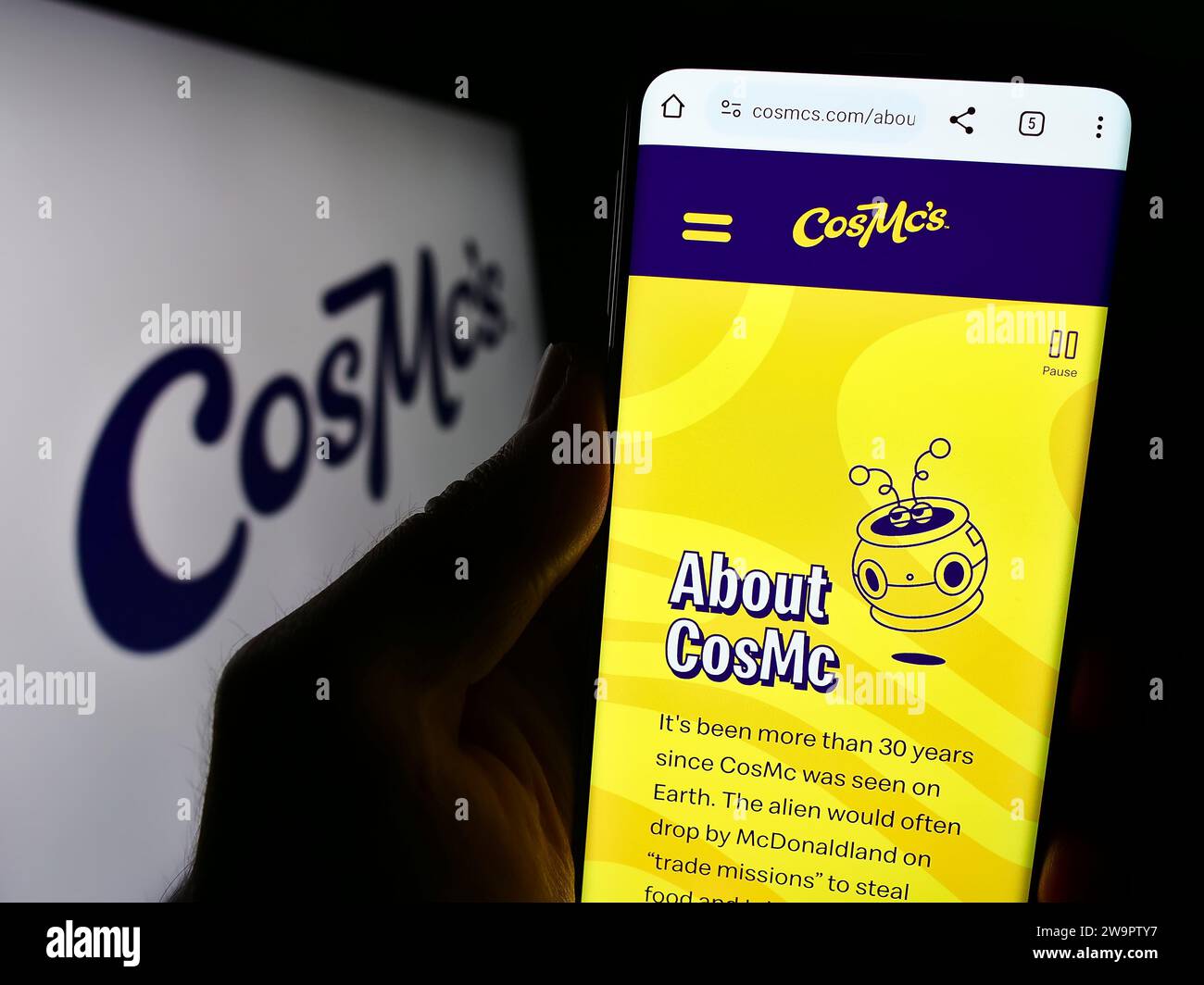 Person, die ein Mobiltelefon hält, mit Website des US-amerikanischen Fastfood-Unternehmens CosMc's (McDonalds) vor dem Logo. Konzentrieren Sie sich auf die Mitte des Telefondisplays. Stockfoto
