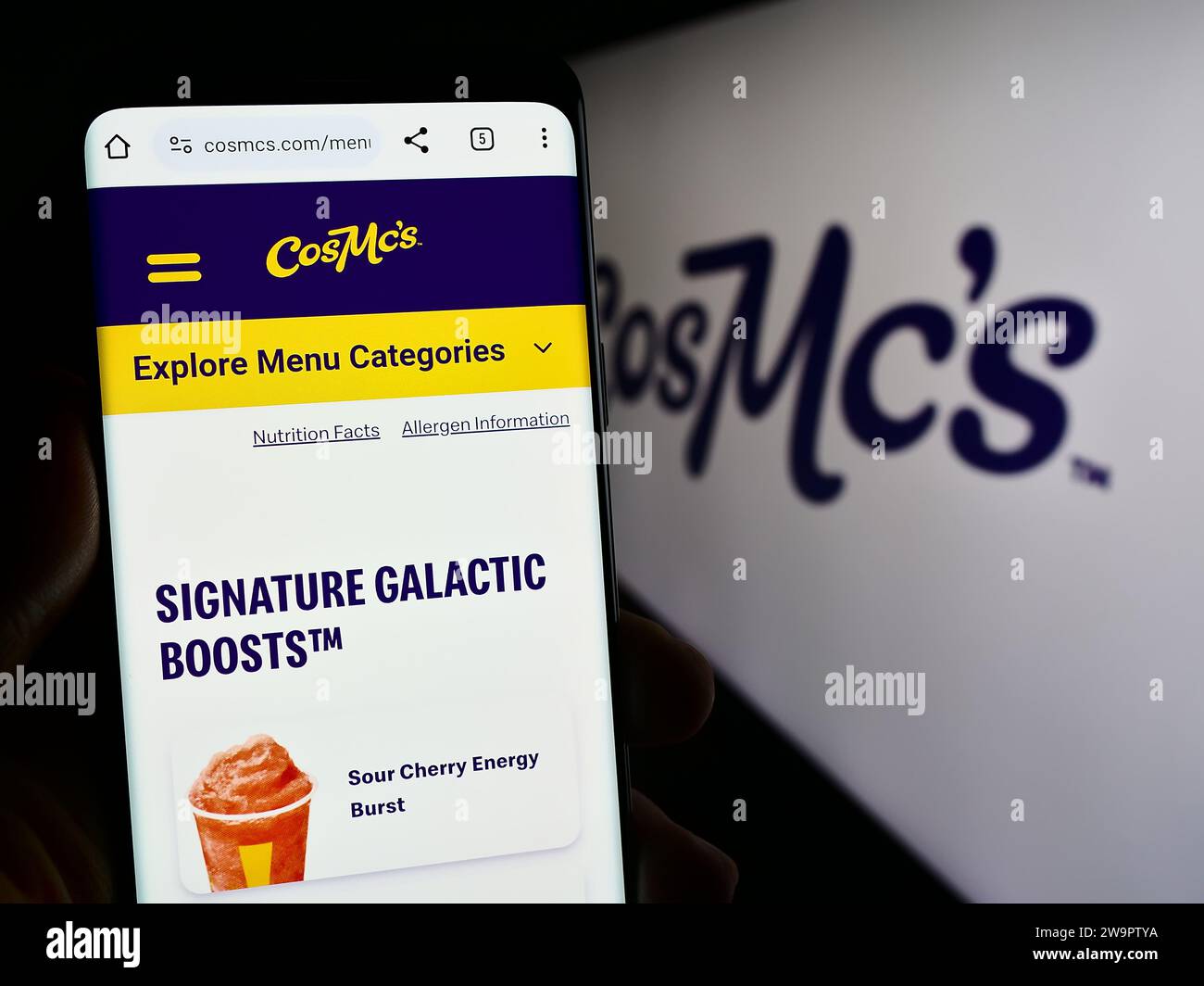 Person, die ein Handy hält, mit Webseite der US-amerikanischen Fastfood-Kette CosMc's (McDonalds) vor dem Logo. Konzentrieren Sie sich auf die Mitte des Telefondisplays. Stockfoto