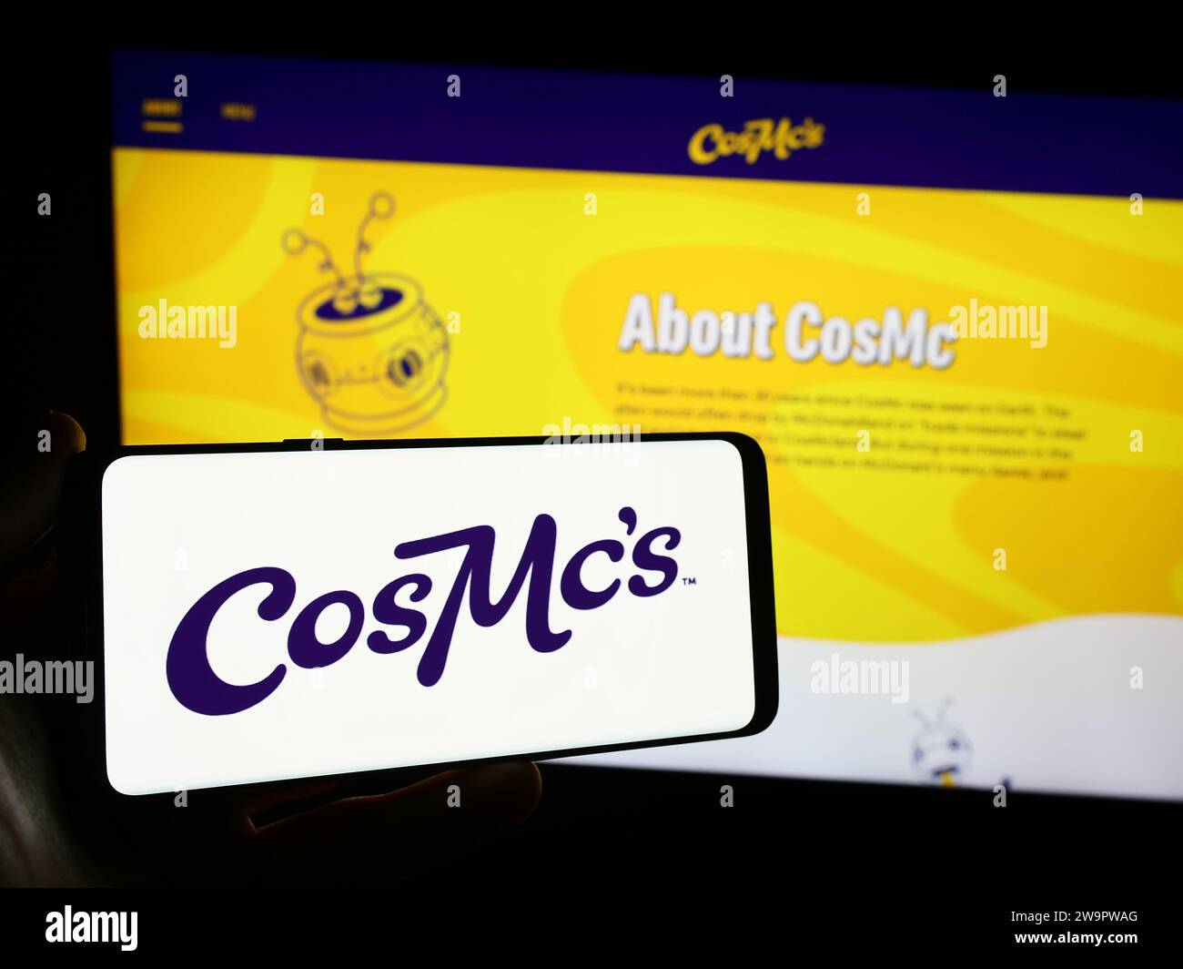 Person, die ein Mobiltelefon mit dem Logo der amerikanischen Fastfood-Kette CosMc's (McDonalds) vor der Webseite hält. Schwerpunkt auf dem Display des Telefons. Stockfoto