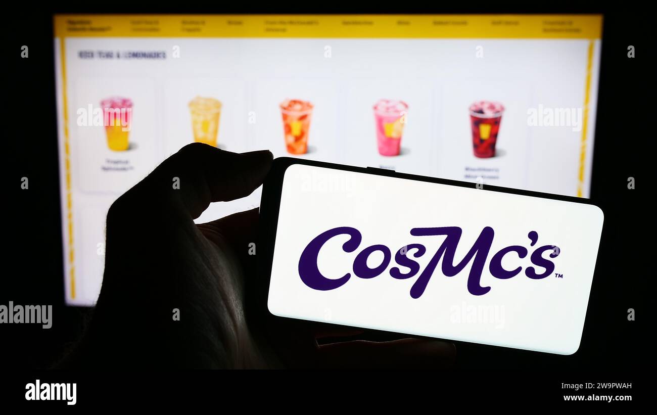Person mit Smartphone und Logo des US-amerikanischen Fastfood-Unternehmens CosMc's (McDonalds) vor der Website. Schwerpunkt auf dem Display des Telefons. Stockfoto
