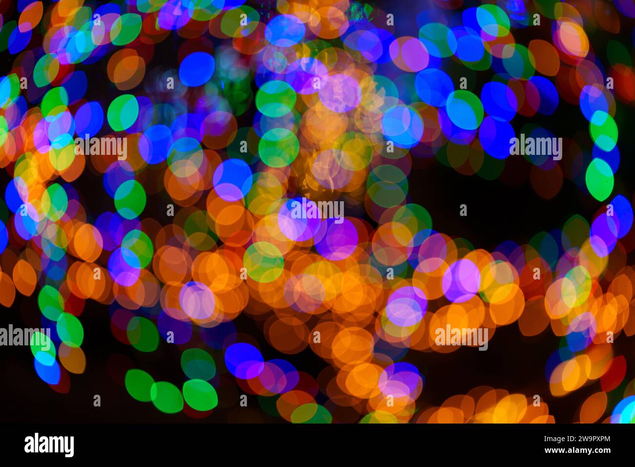 Große Bokeh-Kugeln in leuchtendem Grün, Rot, Orange und Blau wirbeln und kreieren ein magisches Ornament. Abstrakter Hintergrund. Echtes Foto. Stockfoto