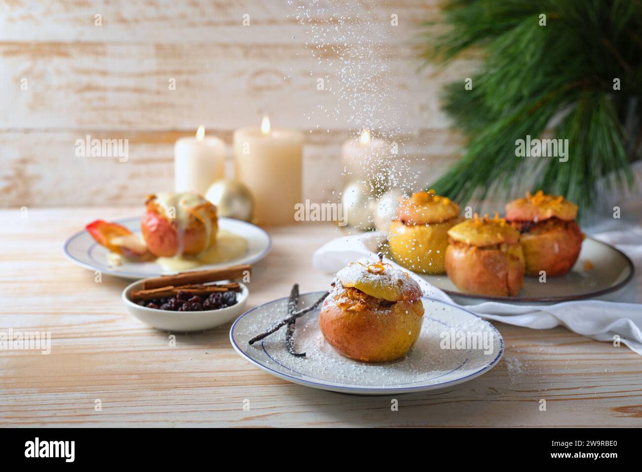 Puderzucker wird auf einen gebackenen Apfel gestreut, der mit Mandeln, Marzipan und Honig gefüllt ist, mit Vanille, Zimt und Orangenschale gewürzt, festlich Stockfoto