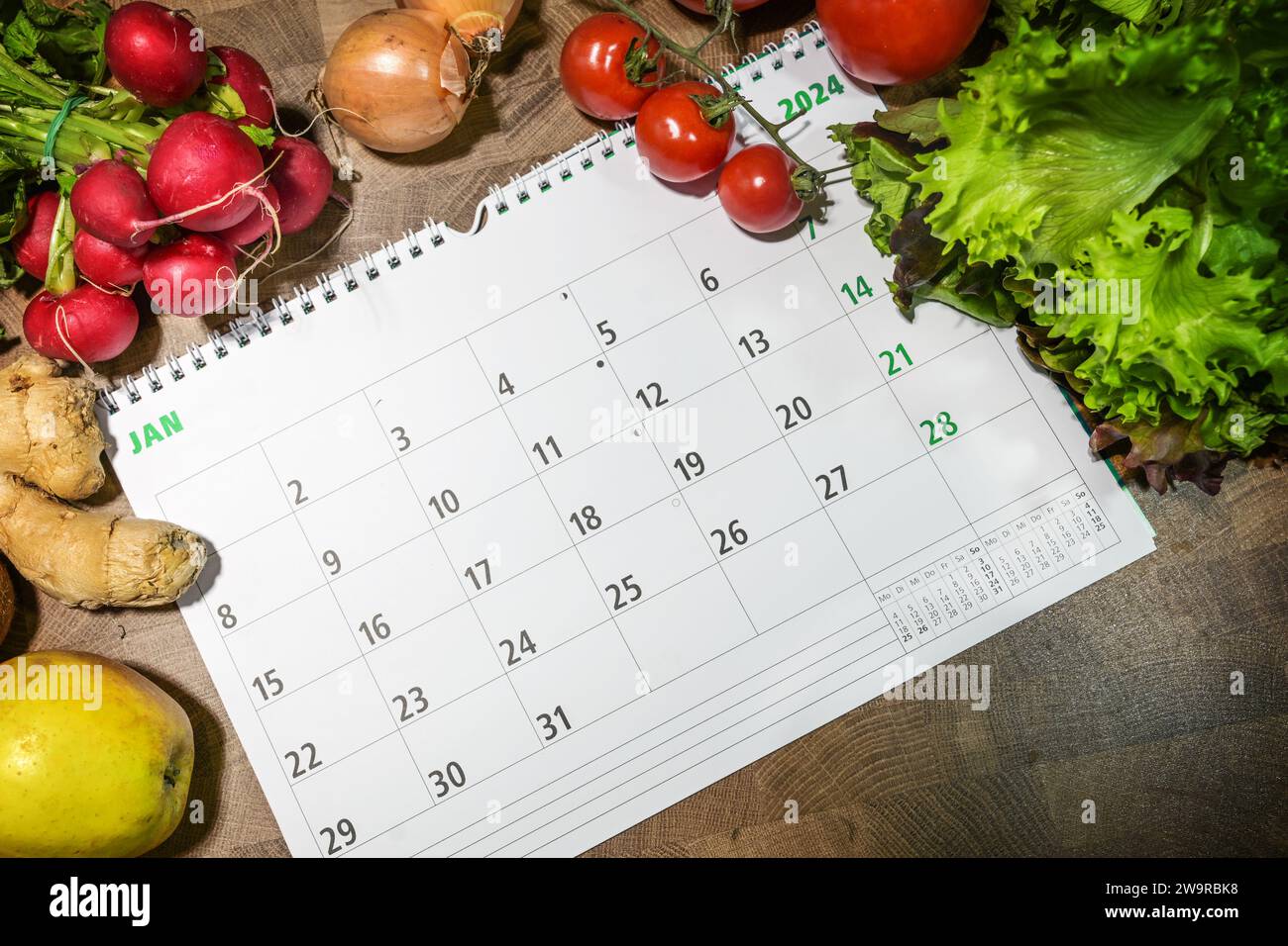 Neujahrsziele, gesund essen und Gewicht verlieren, Januar Monat Kalender umgeben von Gemüse und Obst auf einem Holztisch, von oben Blick, Cop Stockfoto
