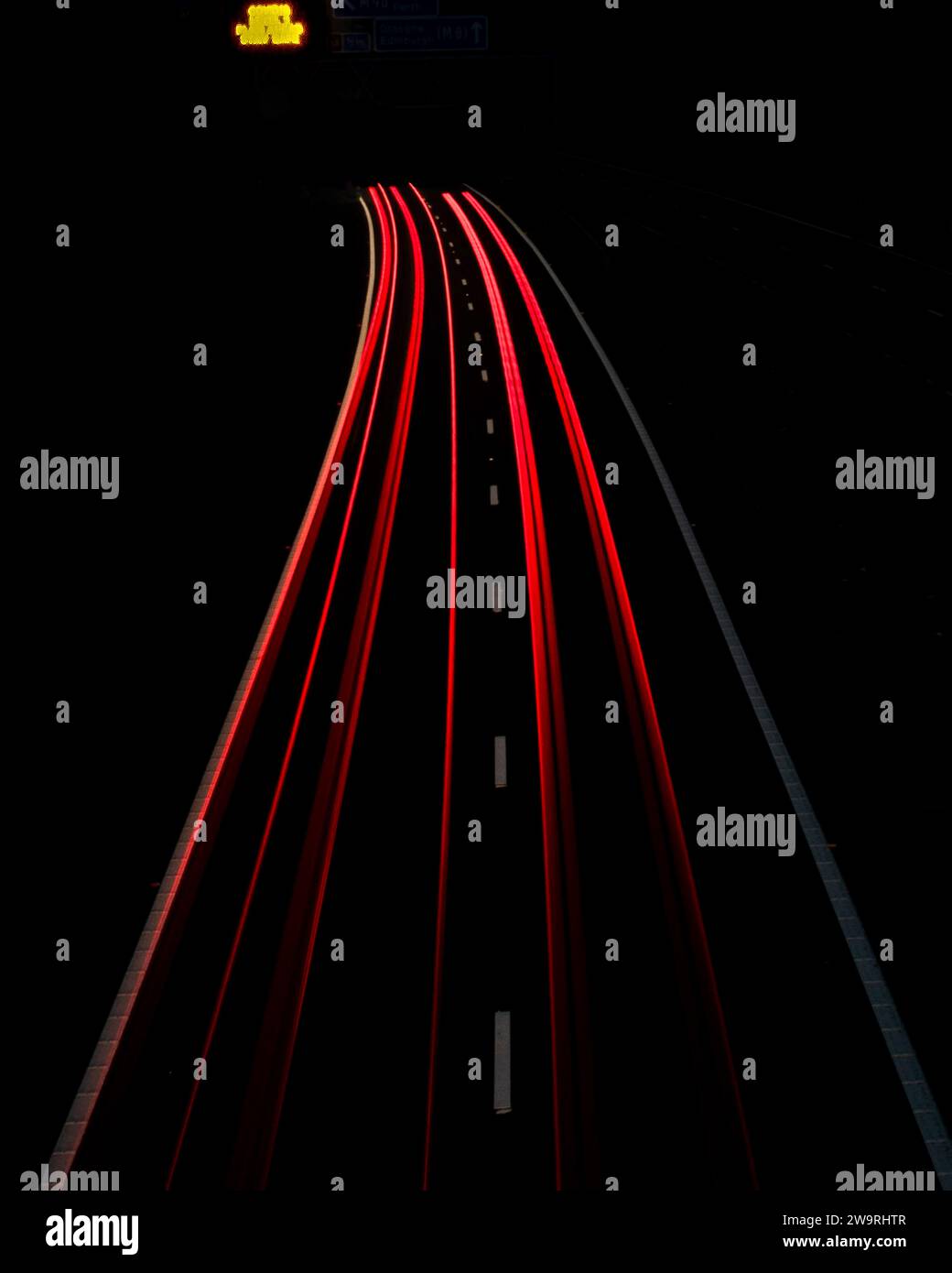 Lange Belichtung bei Nacht – rote Heckleuchten auf der Autobahn M90, West Lothian, Schottland, Großbritannien. Abstraktes Foto. Stockfoto