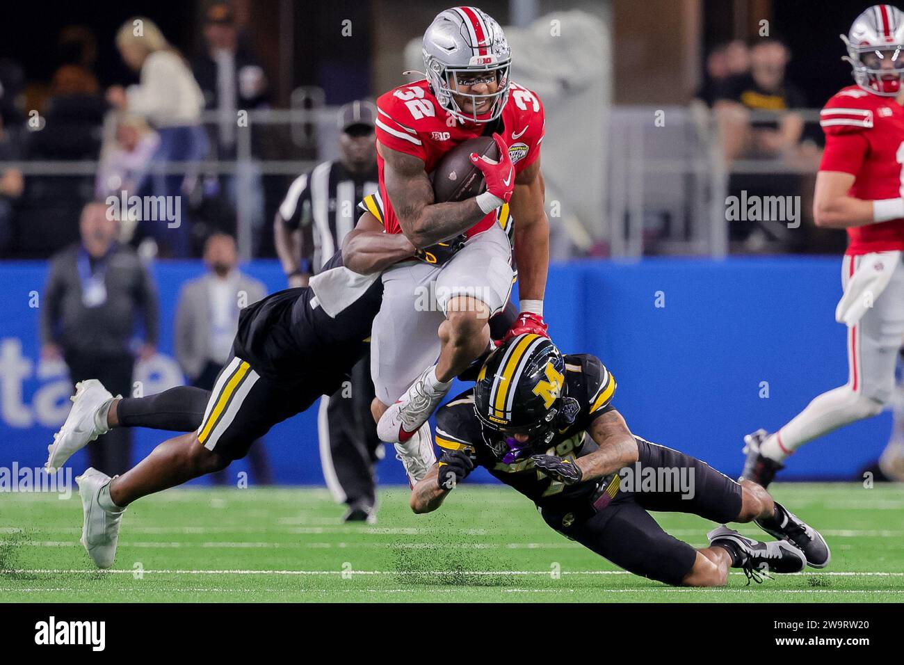 Arlington, Texas, USA. Dezember 2023. DUPLIKAT***Ohio State Buckeyes Sicherheit Brenten Jones (32)***Ohio State Buckeyes Running Back TreVeyon Henderson (32) hüpft im AT&T Stadium in Arlington, Texas, über den Angriff der Missouri Tigers Defensivverteidiger Kris Abrams-Draine (7). (Kreditbild: © Scott Stuart/ZUMA Press Wire) NUR REDAKTIONELLE VERWENDUNG! Nicht für kommerzielle ZWECKE! Stockfoto