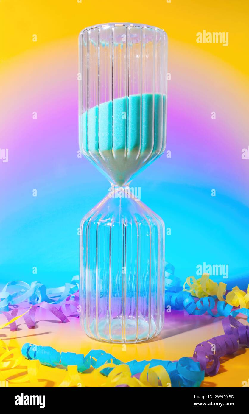 Ein Silvester Countdown-Sand-Timer mit Konfetti- und Party-Streamern auf einem traumhaften, modernen Hintergrund mit Pastel-Farbverlauf Stockfoto