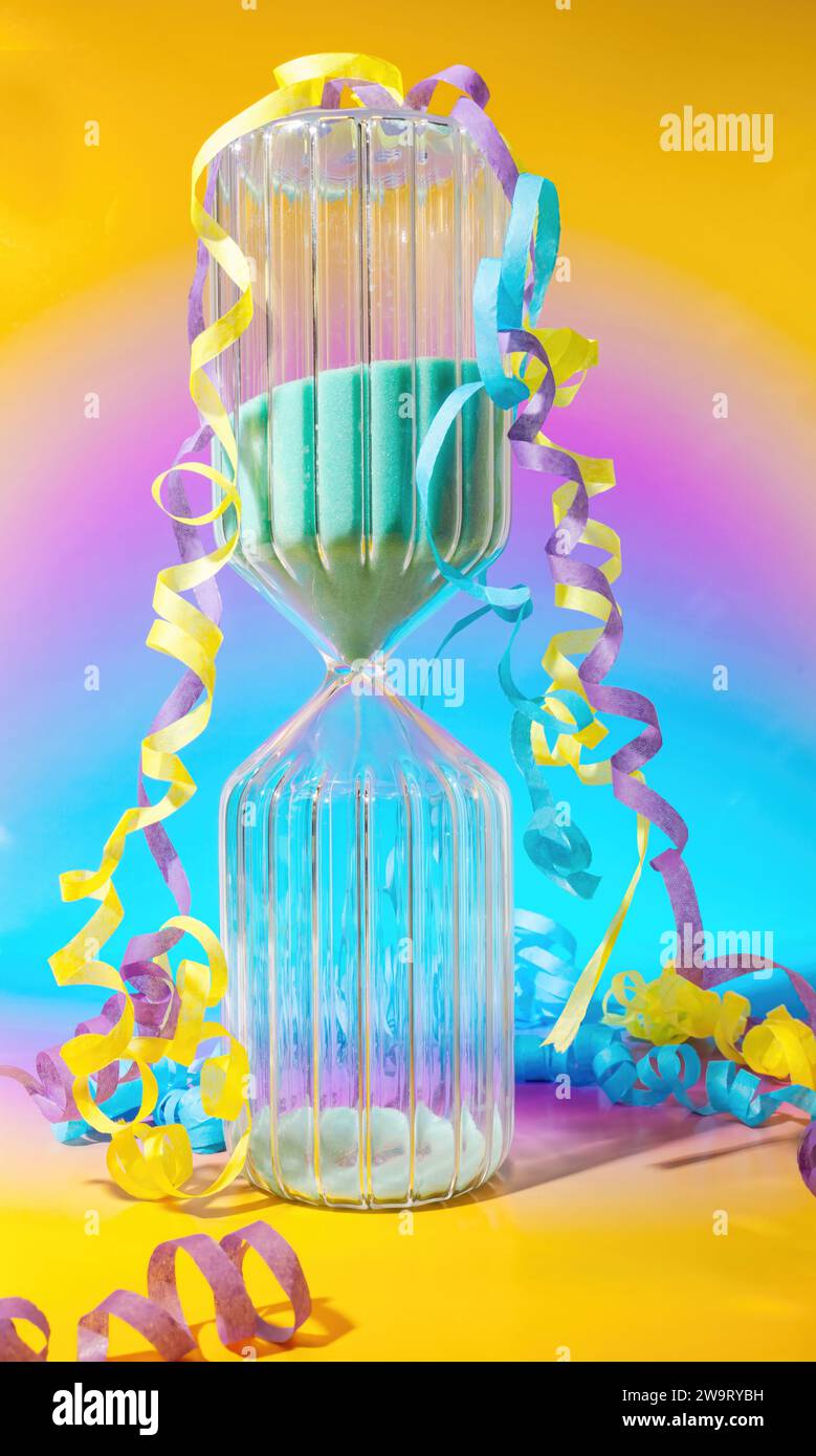 Ein Silvester Countdown-Sand-Timer mit Konfetti- und Party-Streamern auf einem traumhaften, modernen Hintergrund mit Pastel-Farbverlauf Stockfoto