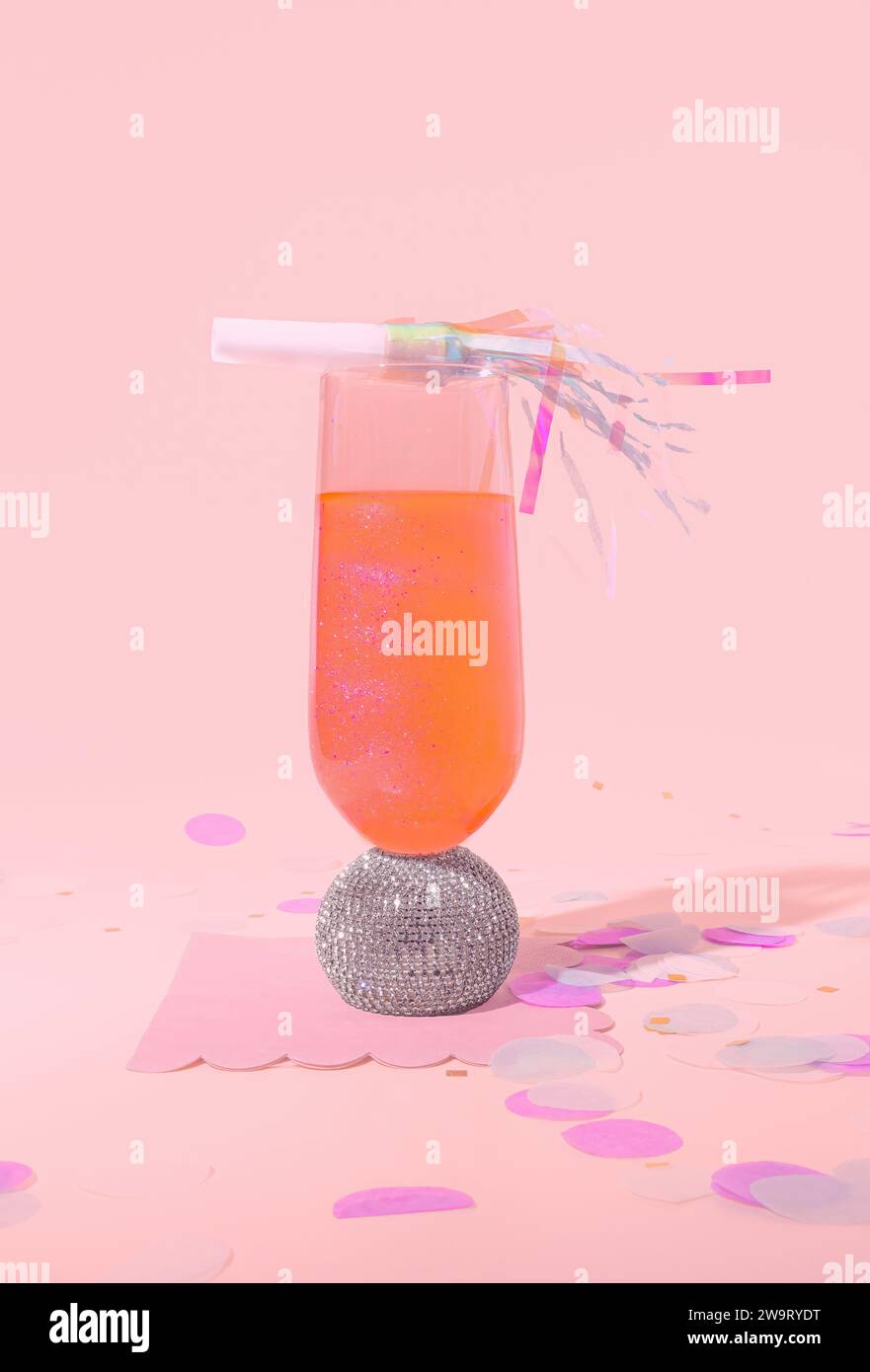 Ein Cocktail mit Orangendiamantbespannung und Glitzer mit Celebration Noise Maker, Konfetti in einer feierlichen Partyszene auf einem Pastel Gradient Backgr Stockfoto