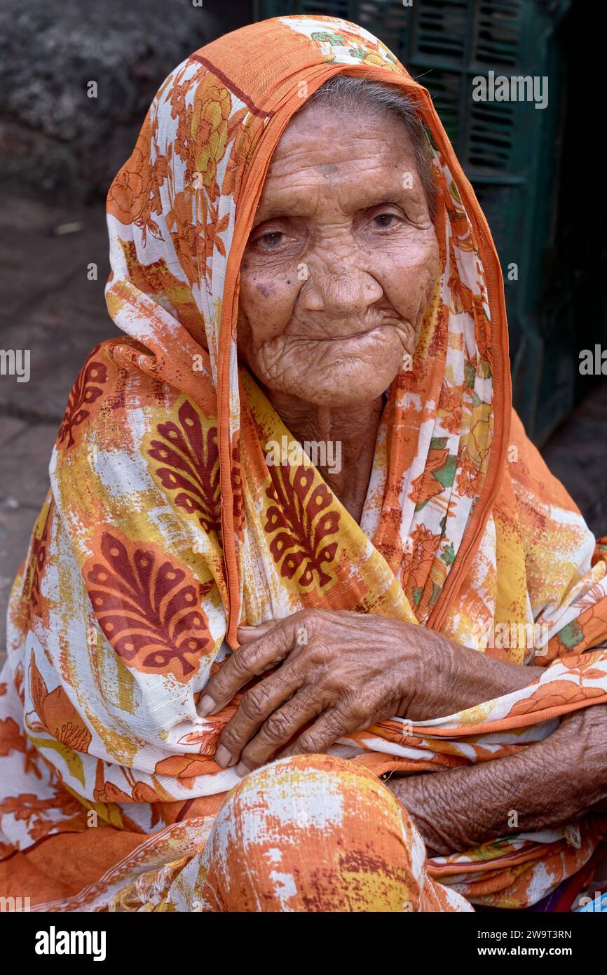 Eine angeblich 91-jährige Frau aus Nashik (Nasik) in Maharashtra, Indien, die Gemüse auf einem Mumbai Markt verkauft und in einem lebhaften, bunten Sari gekleidet ist Stockfoto