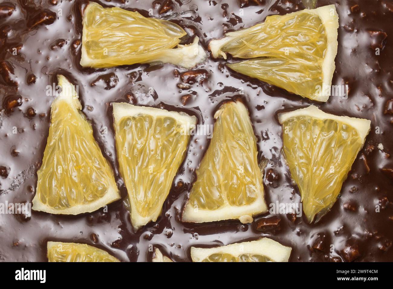 Nahaufnahme von Orangensegmenten auf einem Schokoladen-Kakaokuchen mit Mandeln. Texturen und Speisen. Stockfoto