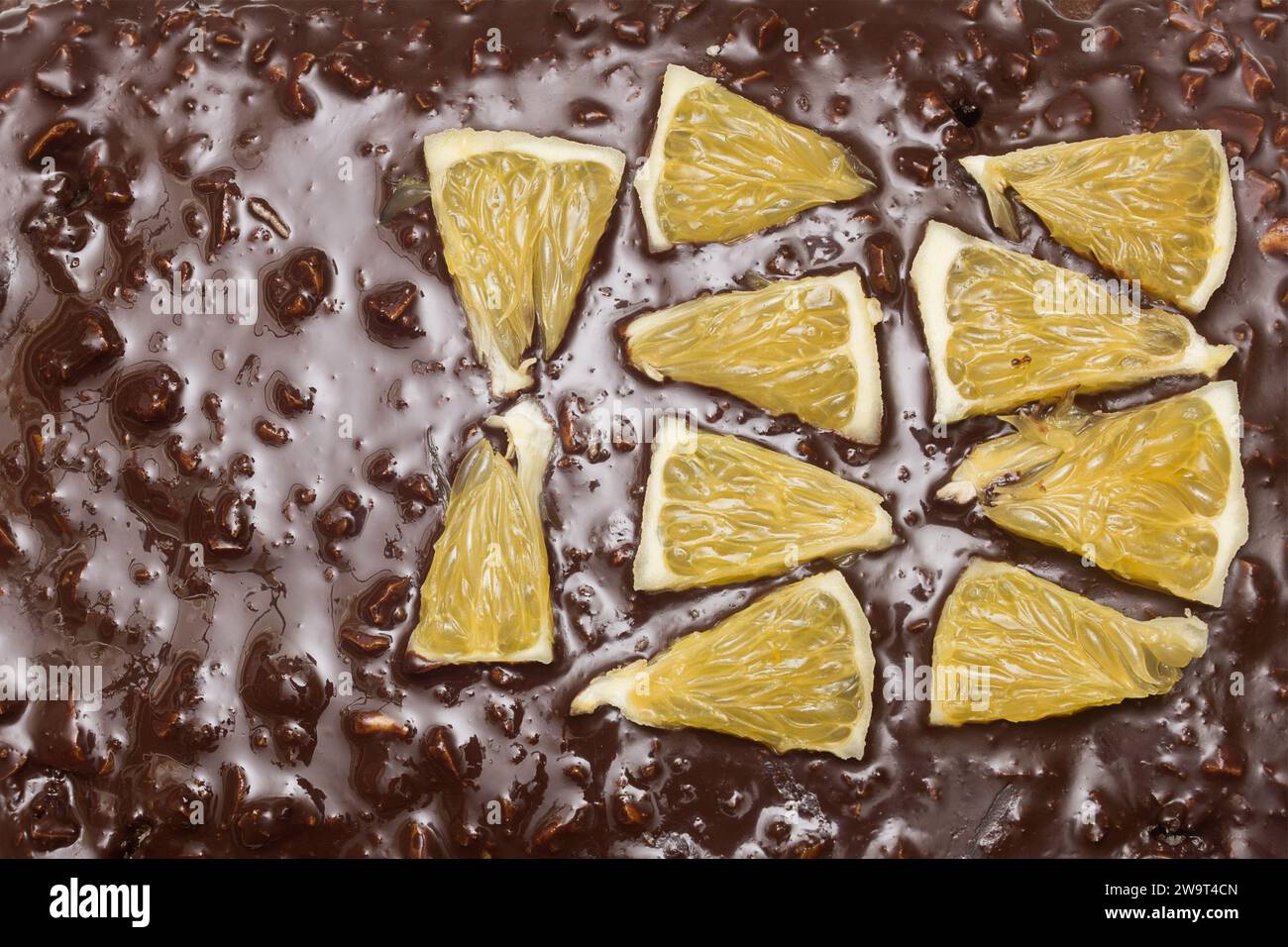 Blick von oben auf die dreieckigen Orangensegmente auf der Schokoladen- und Mandelstruktur eines Kakaokuchens. Textur und Aromen. Stockfoto