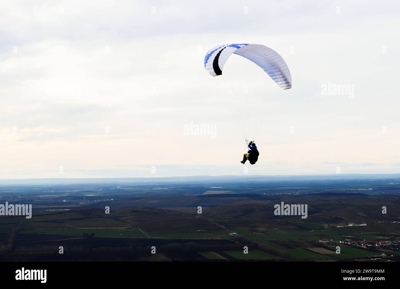 Gleitschirmfliegen auf dem Hügel Pálava in Tschechien. Gleitschirmsilhouette vor Wolken und Himmel. Stockfoto