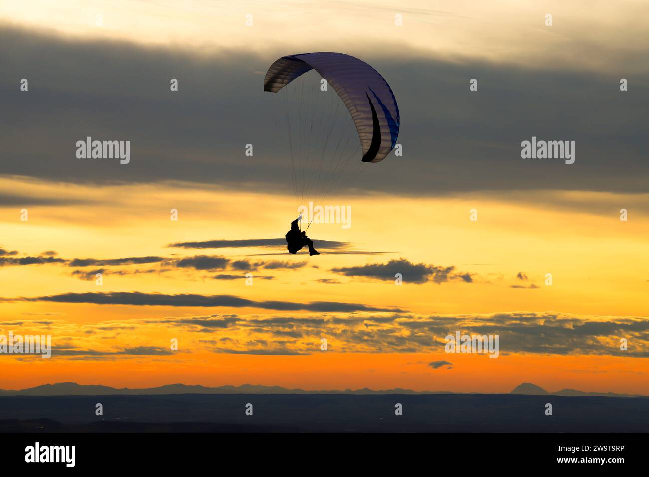 Silhouette des Gleitschirms gegen Sonnenuntergang. Gleitschirmfliegen auf dem Hügel Pálava in Tschechien. Stockfoto