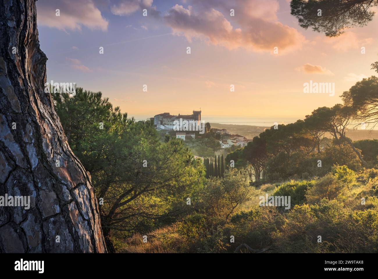 Blick von oben auf die Stadt Rosignano Marittimo und die Burg. Meer im Hintergrund bei Sonnenuntergang. Toskana, Italien Stockfoto