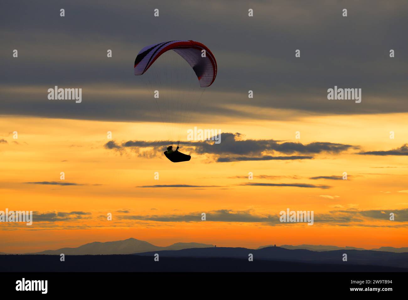 Silhouette des Gleitschirms gegen Sonnenuntergang. Gleitschirmfliegen auf dem Hügel Pálava in Tschechien. Stockfoto