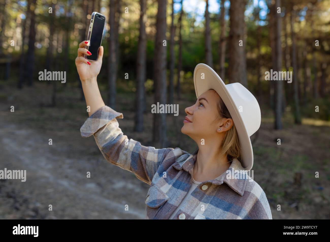 Eine Touristenfrau hält im Wald ein Smartphone-Suchsignal in der Hand. Kommunikation, Probleme mit der Mobilfunkkommunikation, schlechte Verbindung. Da Stockfoto