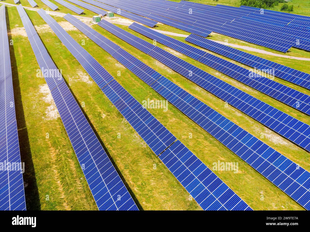 Sonnenkollektoren auf einem grünen Feld aus der Vogelperspektive im Sommer. Alternative Energie. Saubere erneuerbare Energiequellen. Stockfoto