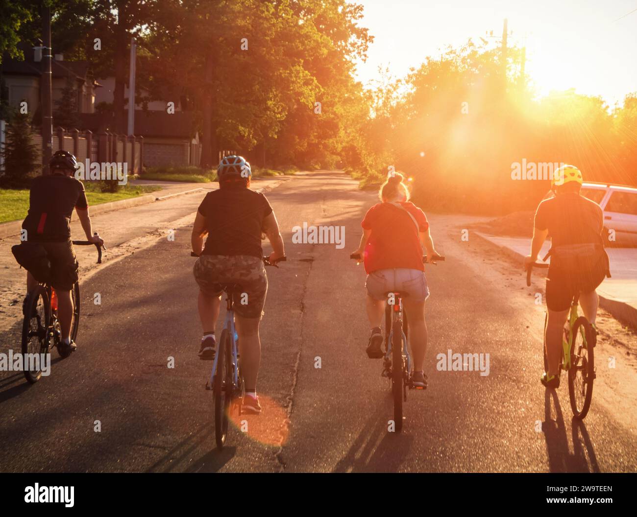 Eine Gruppe von Menschen fährt bei Sonnenuntergang auf der Straße mit dem Fahrrad. Aktives Abhängen mit Freunden. Stockfoto