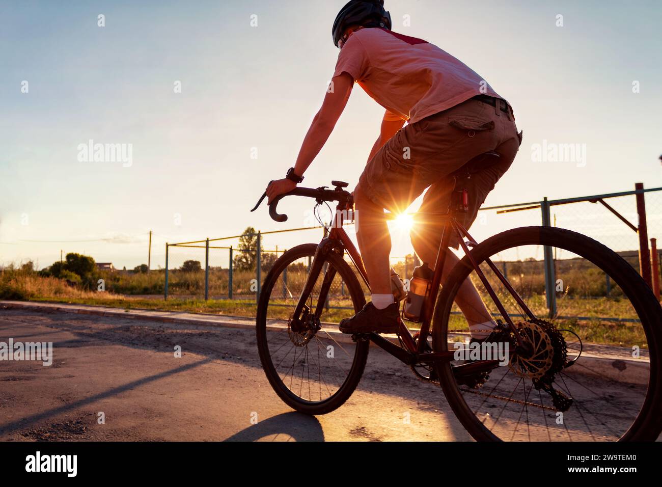 Der Radfahrer fährt mit seinem Fahrrad bei Sonnenuntergang mit Sonnenstrahl. Sport. Aktives Lifestyle-Konzept. Stockfoto