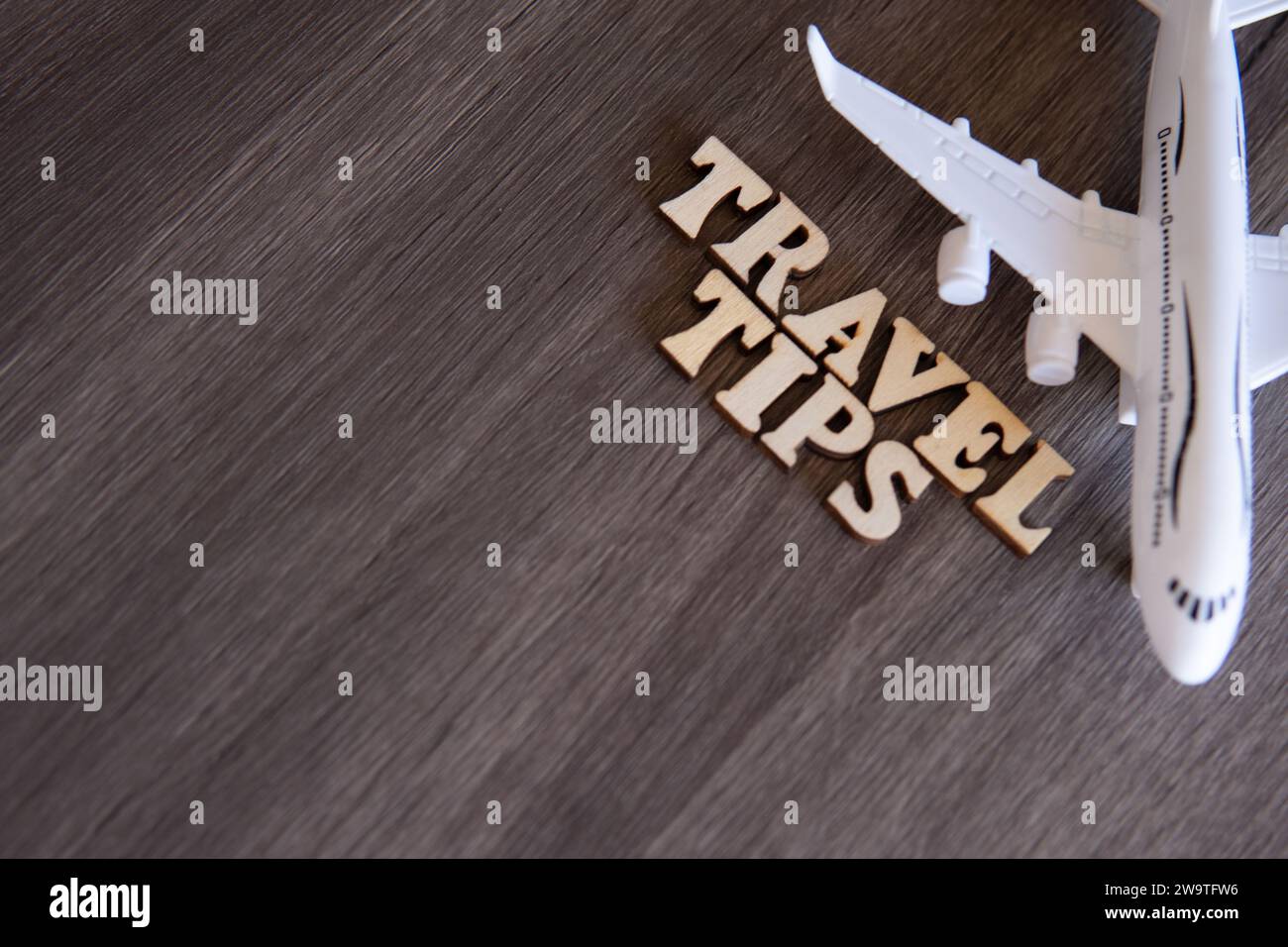 Spielzeugflugzeug- und WORTREISETIPPS auf Holztisch mit Kopierraum für Text. Stockfoto