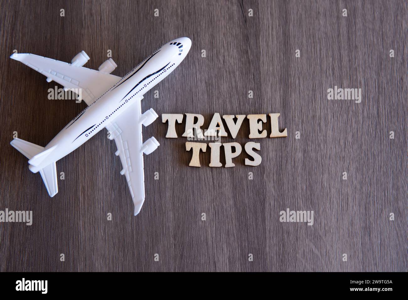 Spielzeugflugzeug- und WORTREISETIPPS auf Holztisch mit Kopierraum für Text. Stockfoto