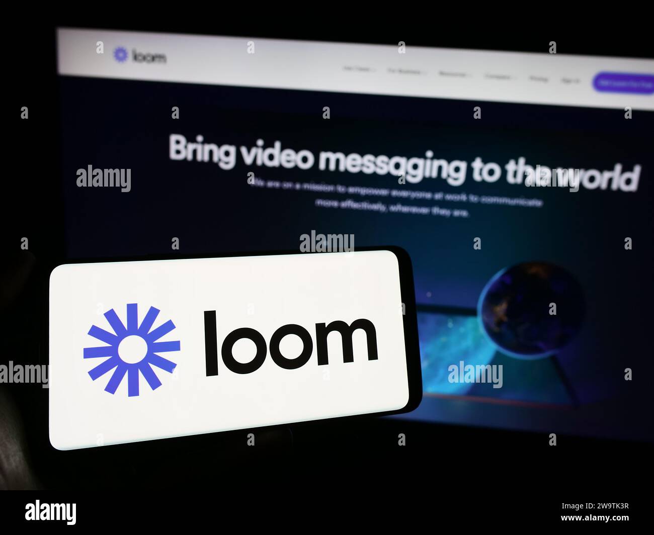 Person, die ein Mobiltelefon mit dem Logo der amerikanischen Videokommunikationssoftware Loom Inc. Vor der Webseite hält. Schwerpunkt auf dem Display des Telefons. Stockfoto