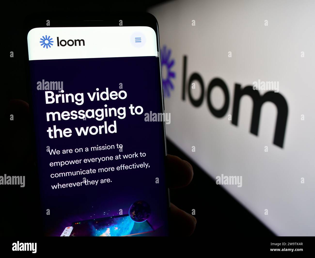 Person mit Smartphone und Webseite des US-amerikanischen Videokommunikationssoftware-Unternehmens Loom Inc. Vor dem Logo. Konzentrieren Sie sich auf die Mitte des Telefondisplays. Stockfoto