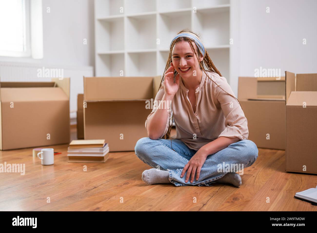 Moderne Ingwerfrau mit Zöpfen zieht in neue Wohnung. Stockfoto