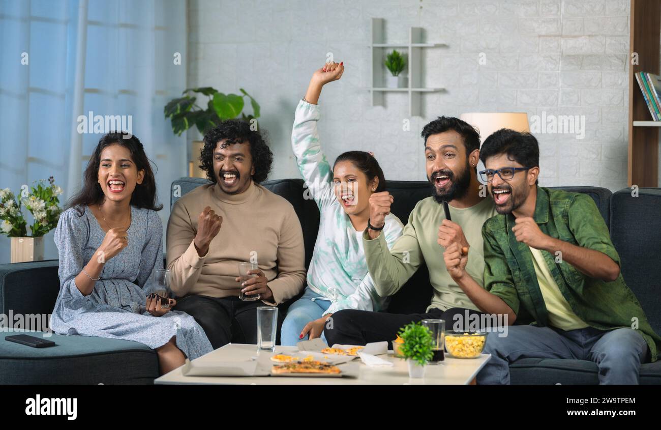 Gruppe junger Sportfans, die den Sieg feiern, während sie live Cricketspiele im Fernsehen zu Hause anschauen – Konzept der Wochenendunterhaltung, Meisterschaft und Stockfoto
