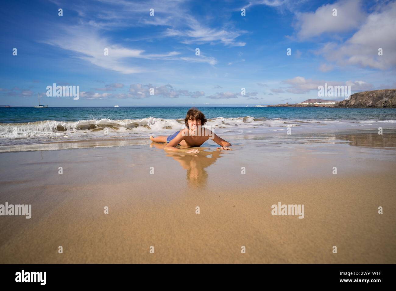 Porträt eines Teenagers, der am Sandstrand des Ozeans liegt. Stockfoto