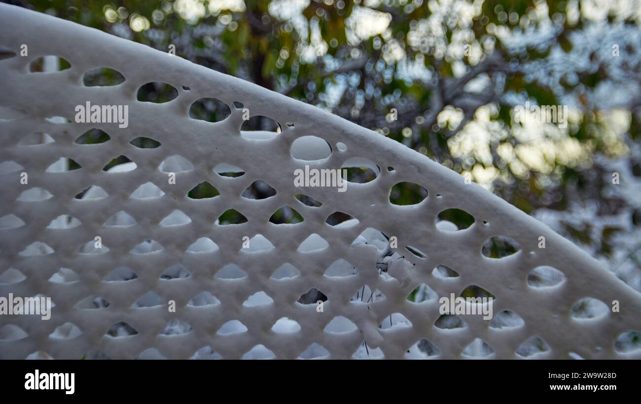 Horizontaler Musterhintergrund von Schneemustern auf einem Metallgitter mit grünem Laub. Der Hintergrund Stockfoto