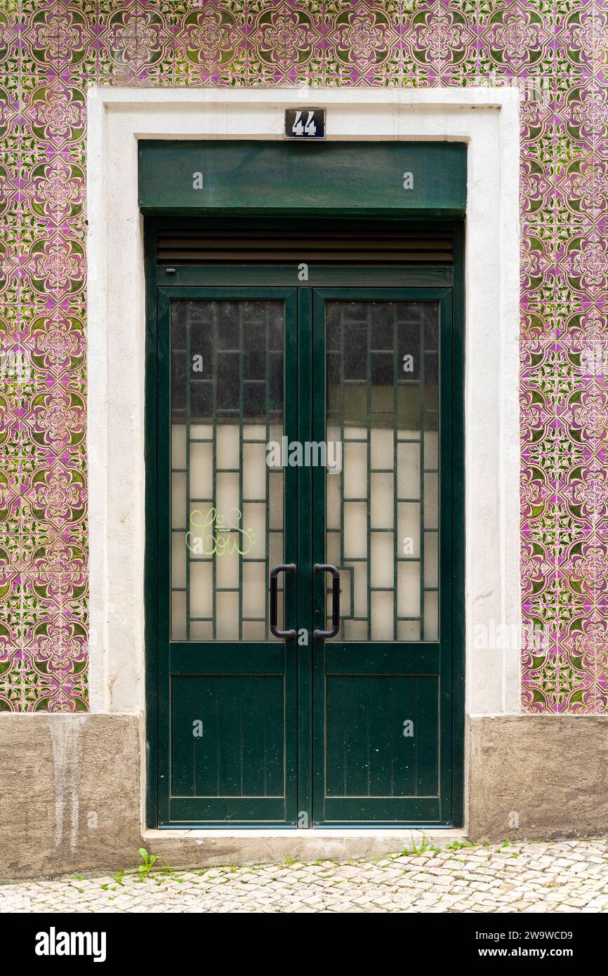Lissabon traditionelle Tür mit rosa und grünen schönen Azulejo-Fliesen mit grünen und rosa Farben. Die Tür hat die Nummer 44 darüber. Weißer Rahmen. Stockfoto
